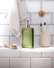 Dispenser of liquid soap and brush on wooden table in bathroom