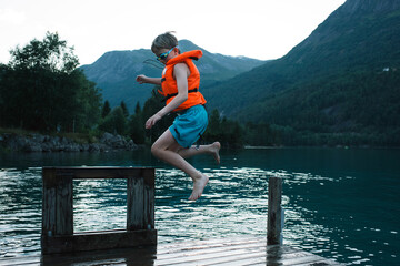 boy jumping into a Norwegian Fjord from a dock