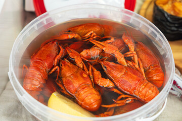 cooked crawfish in saucepan with pickle water with lemons and spices on wooden background