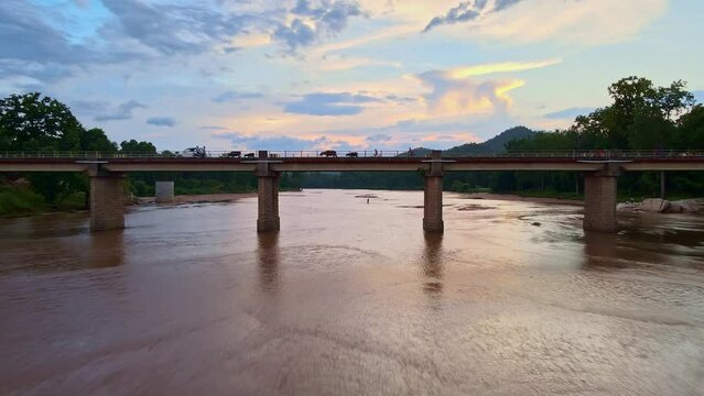 Drone shot of kids and cattle on a bridge over the Koel River as youngsters are walking on the river bed during a beautiful sunset in Jharkhand, India. Cinematic aerial view over a river with abridge 