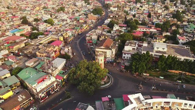 Aerial view of Traffic in Ghantaghar Dehradun, Uttarakhand, Indian City while revealing mountain range in background. 4K Drone shot of Indian Houses in a smart city.