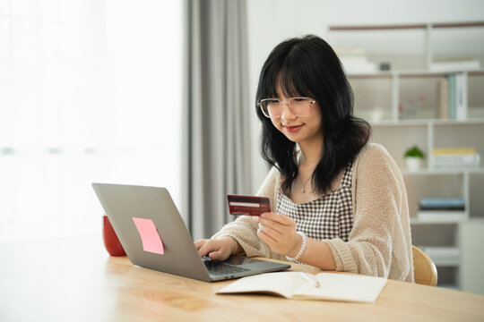 Woman holding showing credit card to shopping online. asian woman working at home. Online shopping, e-commerce, internet banking, spending money, working from home concept.