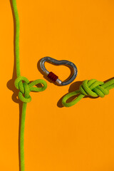 carabiner with a rope lies on a colored background. Equipment for climbing and mountaineering. Safety rope. the concept of reliability and strength.
