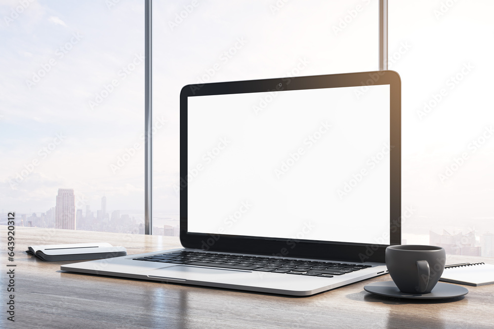 Poster Close up of laptop computer with empty white mock up monitor, coffee cup and notepad placed on wooden desktop. Window with bright city view in the background. 3D Rendering.