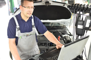 car mechanic maintains a vehicle with the help of a diagnostic computer - modern technology in the...