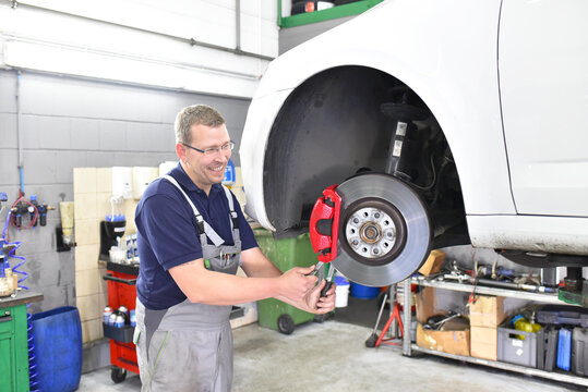 Car Mechanic Repairs Brakes Of A Vehicle On The Lifting Platform In A Workshop