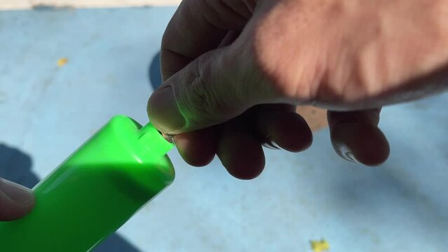 Male hand tighten green inflatable ball pump air needle outdoor sunny day at basketball court with blurred ball on blue ground floor. Sport and recreation concept