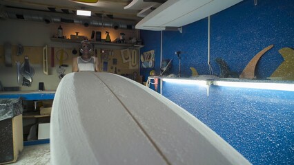 Male surfboard shaper making surfboard in his workshop. Hand shaping from blank.