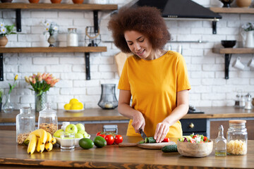 Healthy lifestyle concept. Young  African American woman cooking healthy food while standing in the kitchen at home.