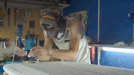 Male surfboard shaper making surfboard in his workshop. Hand shaping from blank.
