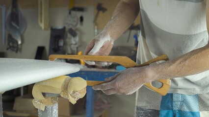 Male surfboard shaper making surfboard in his workshop. Hand shaping from blank.