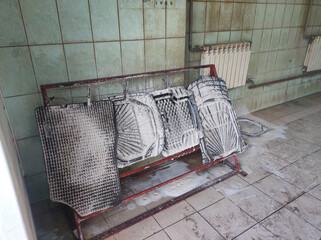 At a self-service car wash, a man rinses car mats from foam with water. The driver meticulously...