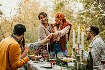 The joyous ambiance of a garden party, with a lesbian proposal with a diverse group of people relishing a shared meal amidst nature's beauty.