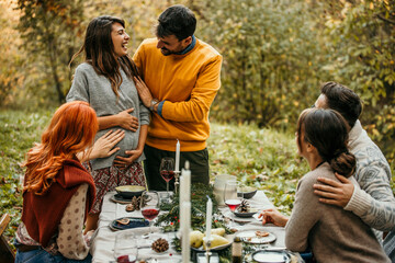 The joyous ambiance of a garden party, with a couple proposal with a diverse group of people relishing a shared meal amidst nature's beauty.