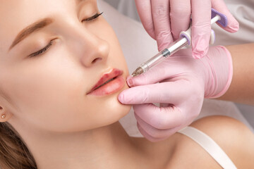 Cosmetologist does injections for lips augmentation anti wrinkle injections on the face of a...
