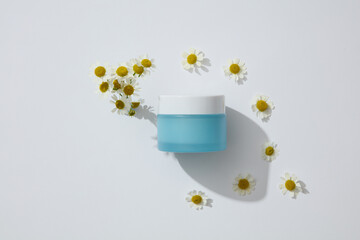 Blue jar without label arranged with white flowers. Chamomilla (Matricaria chamomilla) is a great...