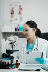 Chemist scientist holding tablet analyzing samples conducting experiment in laboratory with equipment, science concept.