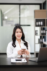 Female asian sitting at the desk, looking to camera.