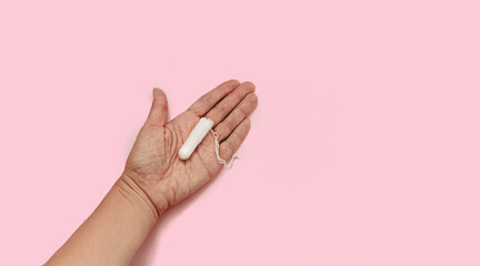 The concept of feminine hygiene, tampons on a pink background. Woman's hand holding a white tampon