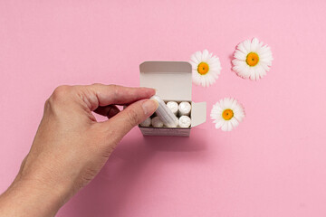 The concept of feminine hygiene, tampons on a pink background. Woman's hand holding a white tampon