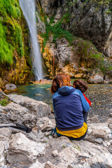 Woman with her child at Grunas waterfall in Theth national park, Albania. Albanian alps