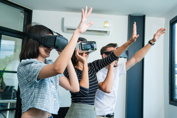 Happy diverse friends  wearing VR goggles while playing video games with hands reaching out to...