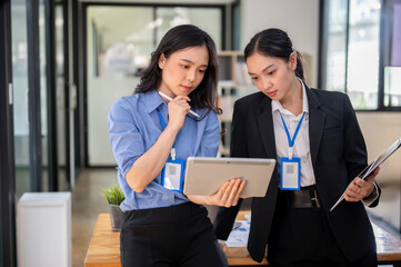 Two beautiful Asian businesswomen are focusing on a co-project, discussing work