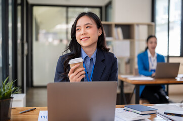 Fototapeta premium A pretty Asian businesswoman is looking out the window and daydreaming about her career success
