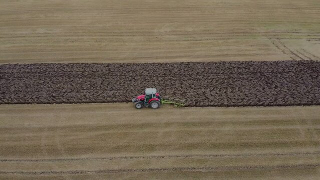 Drone. Harvest time. Tractor plows the soil. Filmed in the summer as the sun is setting. East Yorkshire.UK.  