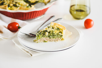 Quiche. Healthy homemade chicken pie with broccoli and spinach on white wooden table