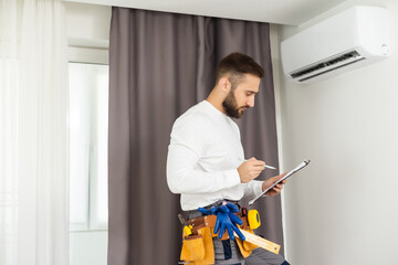 male technician service worker diagnosing for repairs air conditioner. person using tablet.