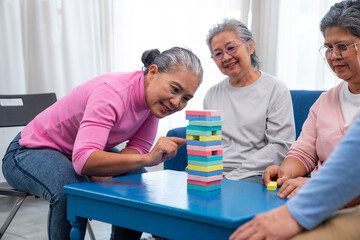 Group of senior people sitting at the table and playing board games together in nursing home