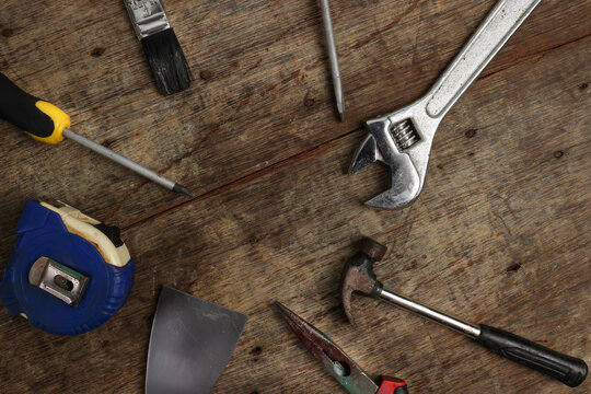 Rusty old tools driver plyer hammer spanner saw on rustic wood background copy space