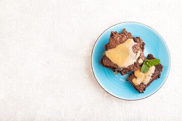 Chocolate brownie with caramel sauce on gray concrete, top view, copy space.