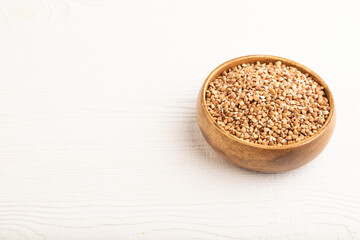 Raw buckwheat on white wooden, side view, copy space