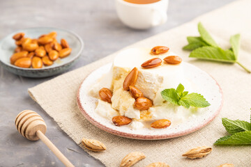 Ricotta cheese with honey and almonds on gray concrete. side view, selective focus.