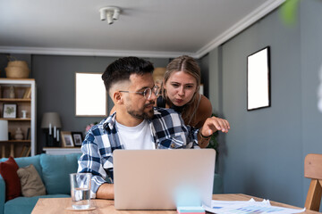 Male student or freelancer trying to work on a laptop and has a video call while his girlfriend is...