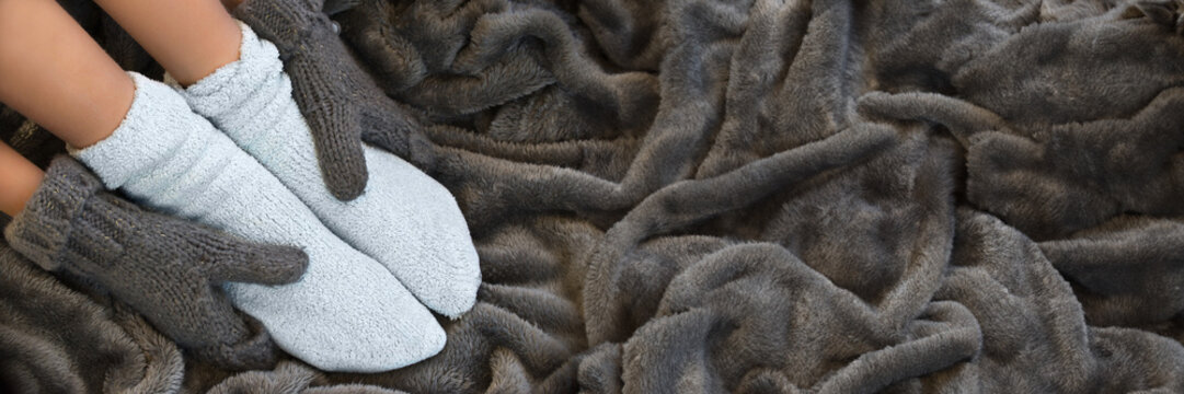 Feet in comfortable and warm woolen socks on a blanket, panoramic winter header