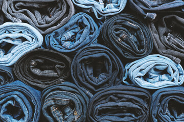 Lots of rolled up jeans. Denim background. Trendy denim clothing, shopping, fashion, consumption.