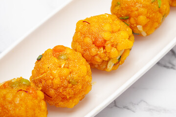 Close-up of an Indian Sweet "Boondi Ladoo" also Called Badi Boondi Ladoo on a white ceramic plate. Front view.