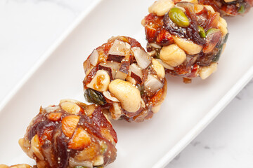 Close-up of Indian classical dry fruits and nuts ladoo (sweet or mithai), on a white ceramic plate. Front view.