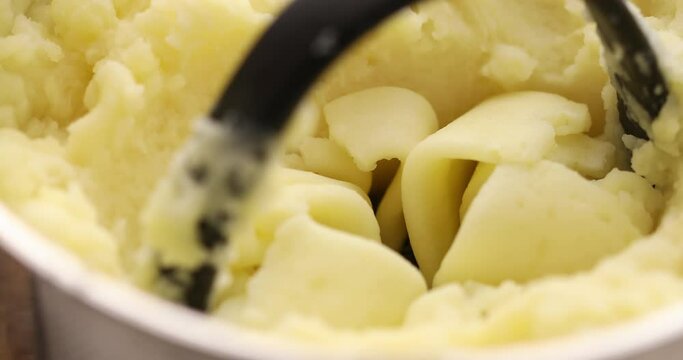 Mashing potatoes in a pot. Cooking food in the kitchen. Boiled vegetables. Vegetarian meal. Close-up.
