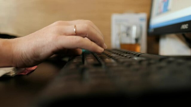 The camera is placed real close to a keyboard, seeing the woman's fingers typing and moving gently over the keyboard's buttons. a close-up 4K video clip.