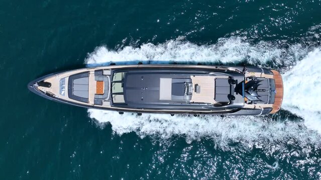 Aerial drone loop video of beautiful modern super yacht with wooden deck cruising in high speed in Aegean deep blue sea