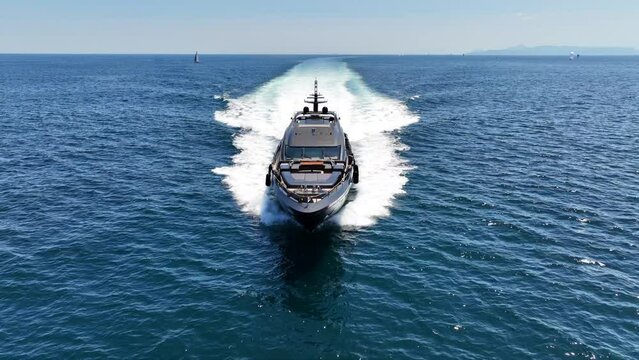 Aerial drone tracking video of beautiful modern super yacht with wooden deck cruising in high speed in Aegean deep blue sea