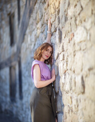 Beautiful successful middle aged woman posing against a stone wall street, photo shoot