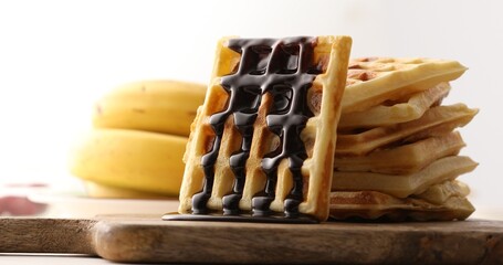 Chocolate pouring on a fresh waffle. Breakfast with Belgian waffles. Sweet food.