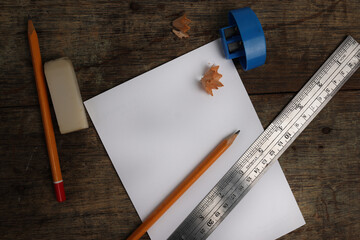 Text copy space paper note pad pencil sharpener rubber eraser metal ruler on rustic wood background