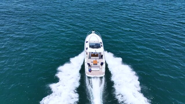 Aerial drone tracking video of beautiful modern super yacht with wooden deck cruising in high speed in Aegean deep blue sea