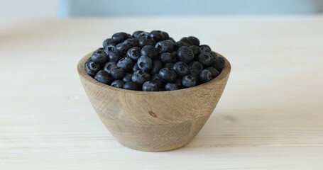 Blueberries in a wooden bowl on a white table. Ripe berries Close-up.